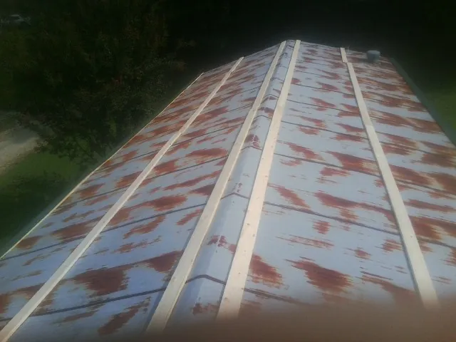 Rusted metal roof panels with new wood purlins before replacement — Storm Damage Roof Repair in Osage by Roofing Brothers