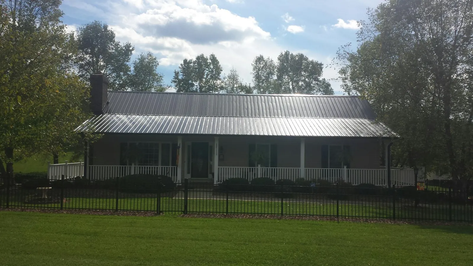 Gray metal roof on a brick ranch with a full width front porch — Gutter Guard Installation work by our crew in Osage