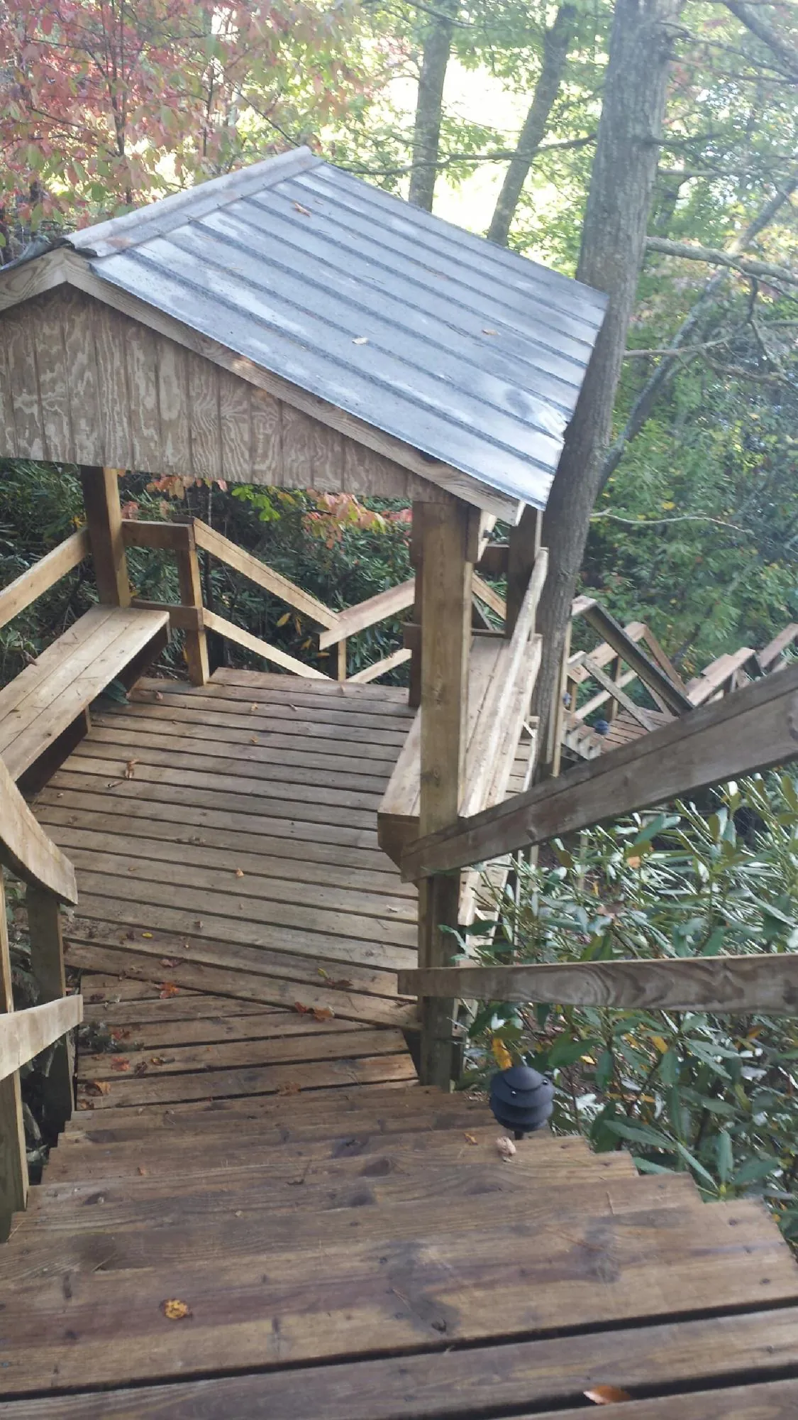Metal roofed shelter over wooden steps on a wooded walkway — Skylight Repair & Installation work by our crew in Osage